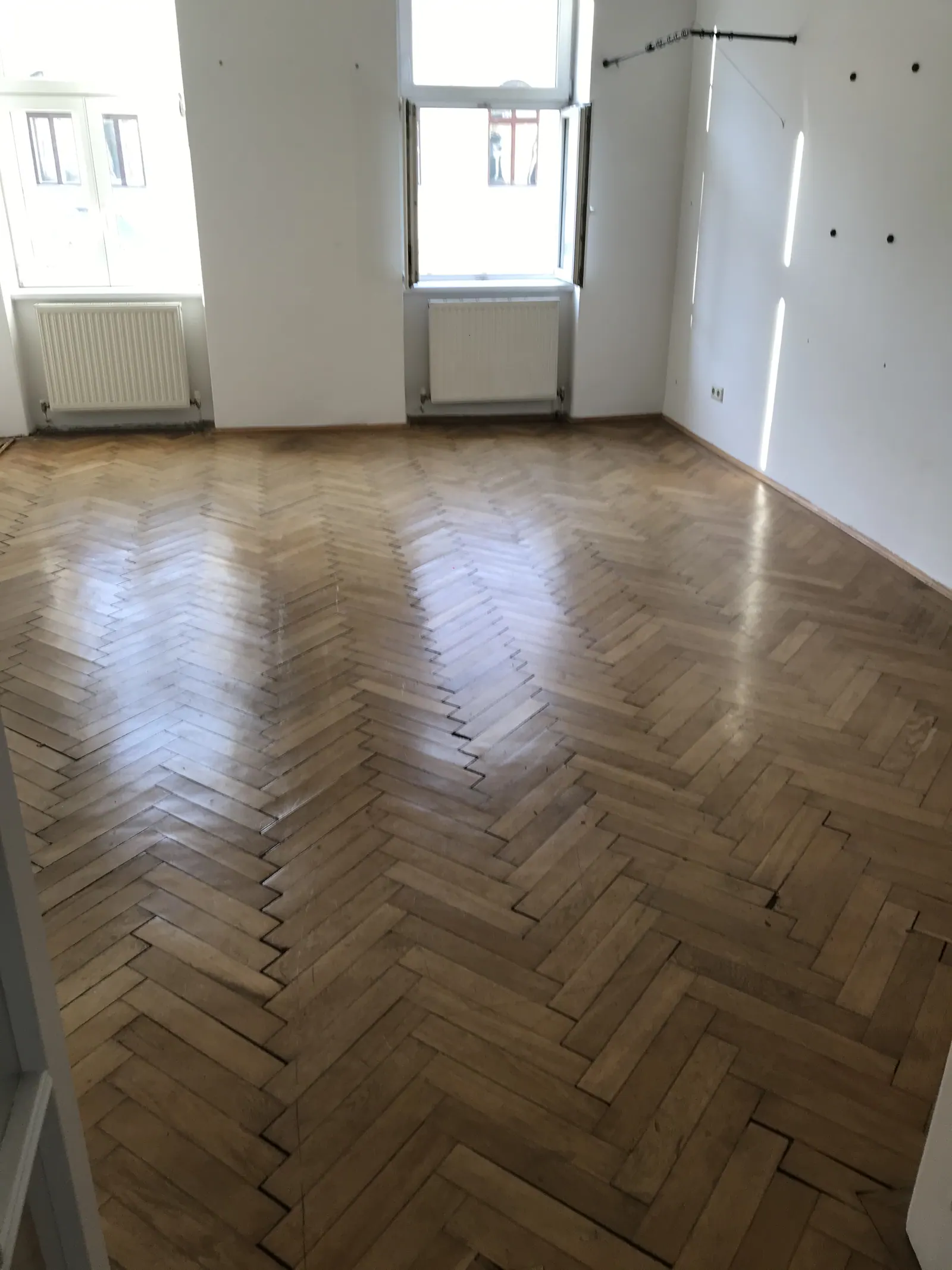 Leergeräumter Wohnraum mit Parkettboden